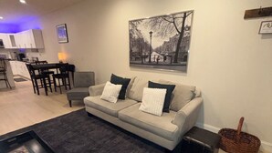 A modern living room with a sofa, coffee table, and a painting on the wall.