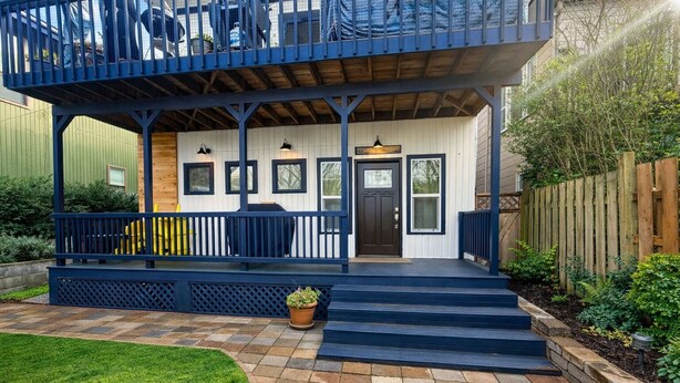 A two-story house with a porch, a front door, and a small garden area.