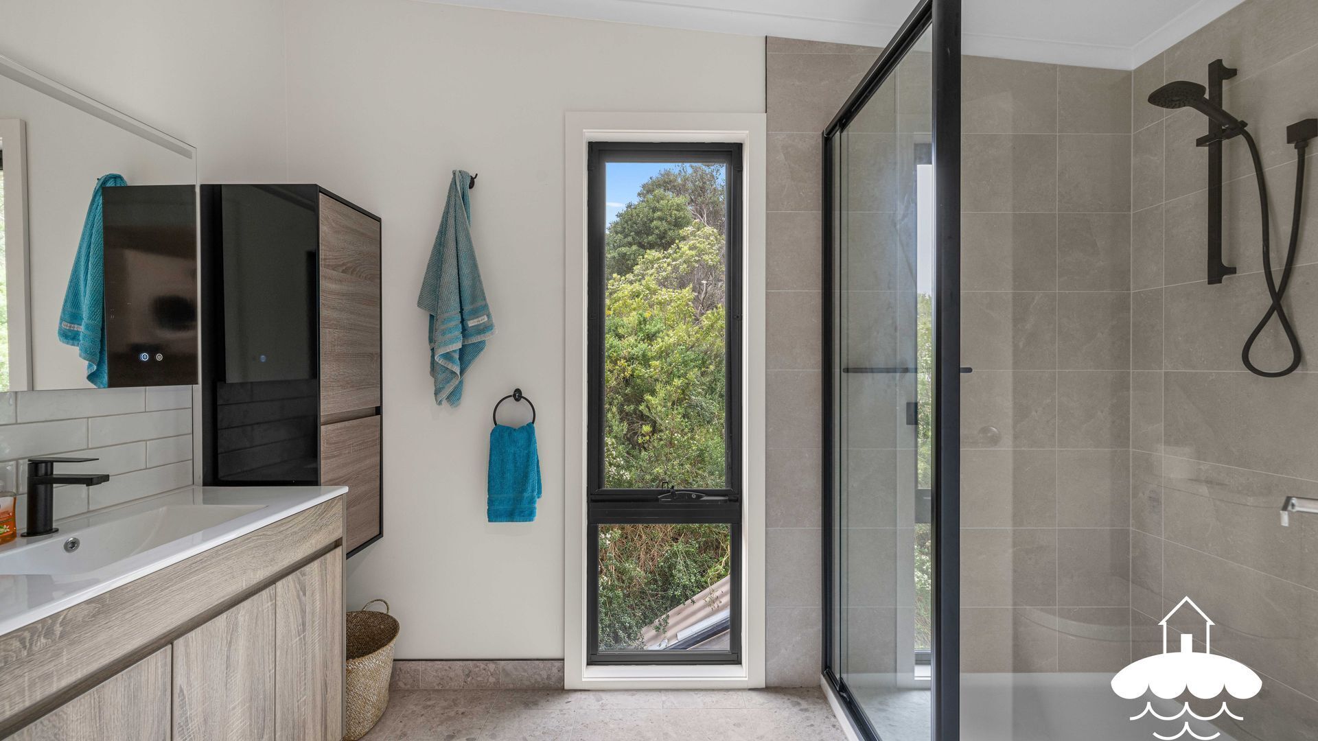 A modern bathroom with a shower, a window, and a sink.