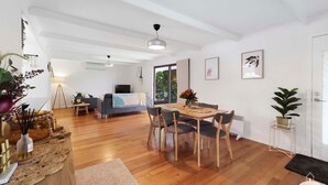 Un salon moderne avec un coin repas, un plancher en bois et une grande fenêtre.