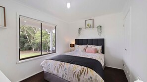 A bedroom with a large window, a bed with a dark headboard, and a small bedside table with a lamp. - Between Waters Stay 3 Pay 2 Winter Special (Yanakie)