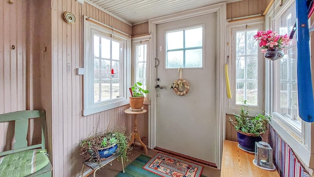 Un hall d’entrée accueillant, avec une porte en bois, des plantes en pot, une petite table et une chaise.