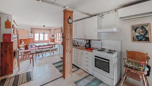 Une cuisine compacte avec des meubles blancs, une cuisinière et un coin repas comprenant une table et des chaises en bois.
