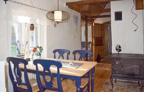 Ein Essbereich mit einem Holztisch, blauen Stühlen und einer Pendelleuchte.