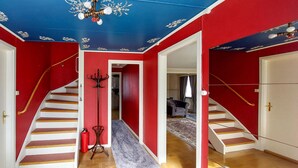A staircase with white steps and red walls, a coat rack, and a fire extinguisher.