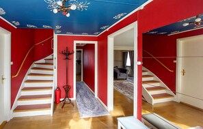 A staircase with white steps and red walls, a coat rack, and a fire extinguisher.