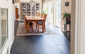 A dining area with a wooden table and chairs, a chandelier, and a view of the outdoors. - Cozy home in åsa with sauna (Åsa)
