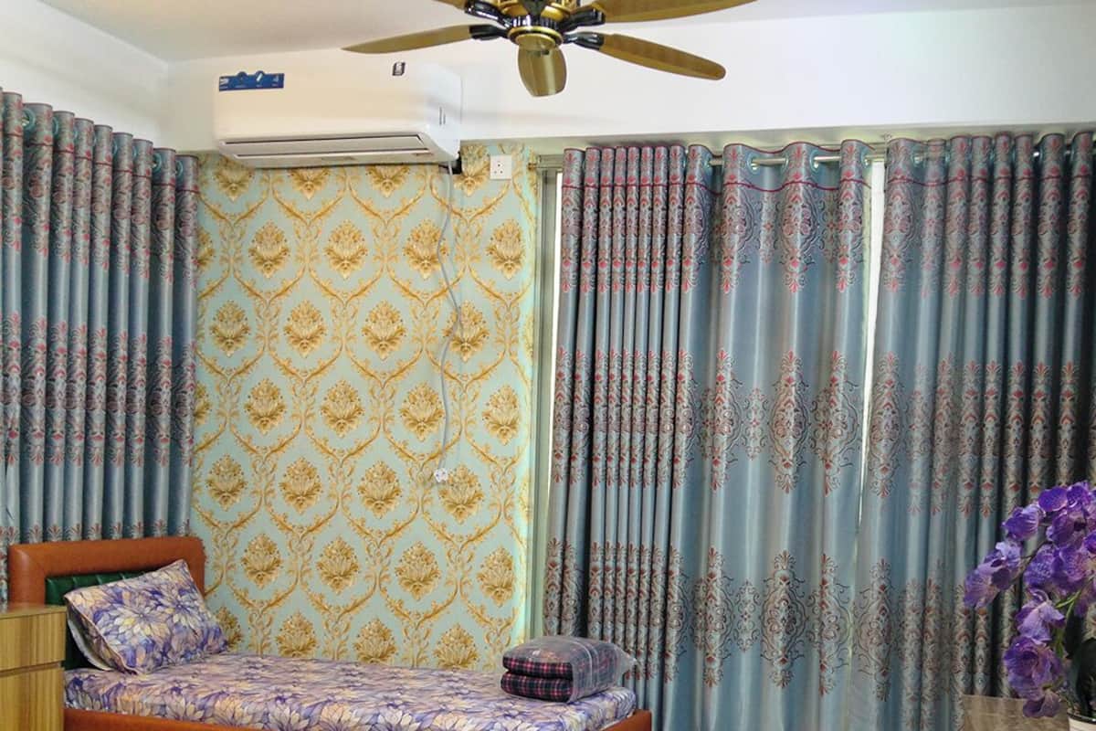 Ein Schlafzimmer mit einem Bett, einer kleinen Couch, einem Deckenventilator und Vorhängen.