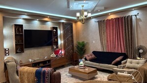 Ein modernes Wohnzimmer mit Fernseher, einer Couch, einem Couchtisch und einer Zierpflanze.