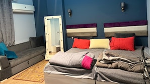 Ein Schlafzimmer mit einem Bett, einem Schminktisch mit Beleuchtung, einem Sofa und einem Spiegel.