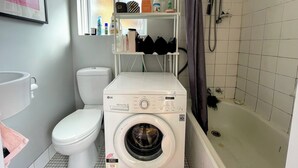 Ein kleines Badezimmer mit Waschmaschine, Toilette und Dusche.