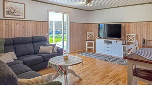 Ett vardagsrum med en soffa, ett litet bord, en tv och ett träskåp.