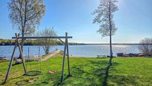 En gräsyta med en gunga och ett picknickbord vid en sjö.
