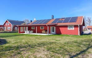 A red house with solar panels on the roof, a covered porch, and a stone wall. - Gorgeous home in Vittaryd with sauna (Vittaryd)