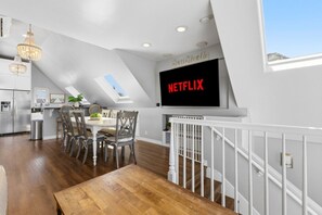 Eine moderne Küche mit Essbereich, einer Treppe und einem großen Bildschirm, der 'NETFLIX' zeigt.