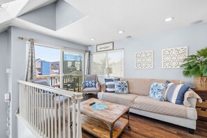Ein Wohnzimmer mit einer Couch, einem Couchtisch und einem Balkon mit Geländer.