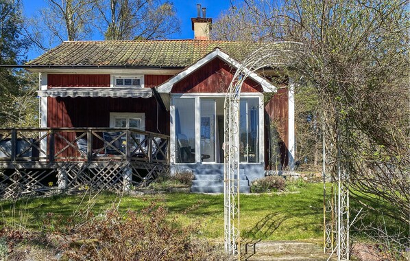 A wooden house with a porch, a glass door, and a metal railing.