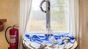 Ein Fenster mit einem Kranz, einem Feuerlöscher und einem Tisch mit blauem Tuch und einer Schwaneinrichtung.