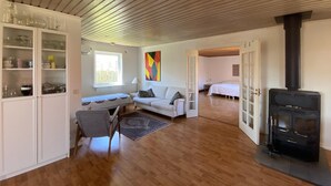A cozy living room with a sofa, a dining table, a chair, a fireplace, and a kitchen area with cabinets. - 3 bedroom stunning home in Mörbylånga (Mörbylånga)
