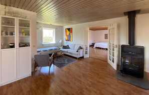 Un salon confortable avec un canapé, une table à manger, une chaise, une cheminée et un coin cuisine équipé de placards.