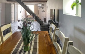 A dining area with a wooden table, chairs, a striped rug, and a plant centerpiece.