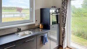 Eine Küche mit Fenster, Spüle, Messerblock und Blick auf einen Zaun und Bäume.