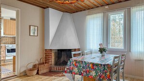 A dining area with a fireplace, a table with a colorful tablecloth, wicker baskets, and a view of the outside through large windows. - 2 bedroom amazing home in Visby (Visby)