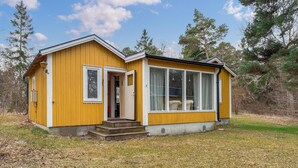 A yellow cabin with a large window, a door, and a small porch. - 2 bedroom amazing home in Visby (Visby)