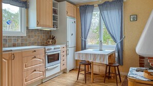 A kitchen with wooden cabinets, a stove, a refrigerator, a window with curtains, and a table with stools. - 2 bedroom amazing home in Visby (Visby)