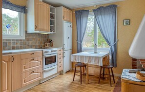 A kitchen with wooden cabinets, a stove, a refrigerator, a window with curtains, and a table with stools. - 2 bedroom amazing home in Visby (Visby)