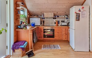 A compact kitchen with wooden cabinets, a built-in oven, a white refrigerator, and a tiled backsplash. - Awesome home in Uddevalla with sauna (Uddevalla)
