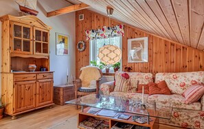 A cozy room with a wooden cabinet, a glass table, a floral sofa, and a wicker chair. - Awesome home in Uddevalla with sauna (Uddevalla)