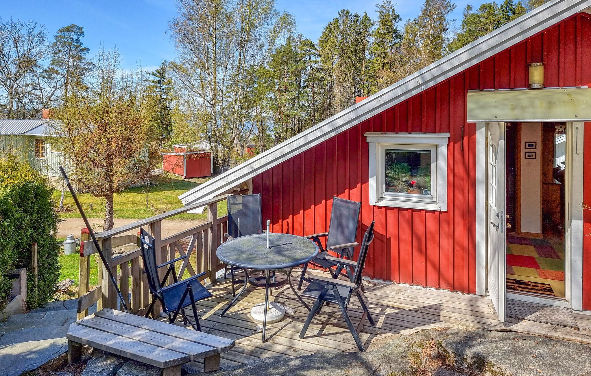 A red building with a deck, a round table, and chairs.