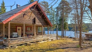 A wooden cabin with a porch, a fireplace, and a view of a lake. - Awesome home in Grythyttan with lake view (Grythyttan)