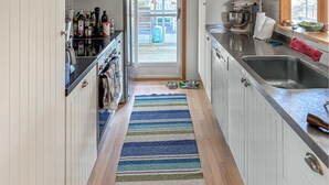 A narrow kitchen with a striped rug, a sink, and various kitchen appliances. - Gorgeous home in Värmdö (Värmdö)