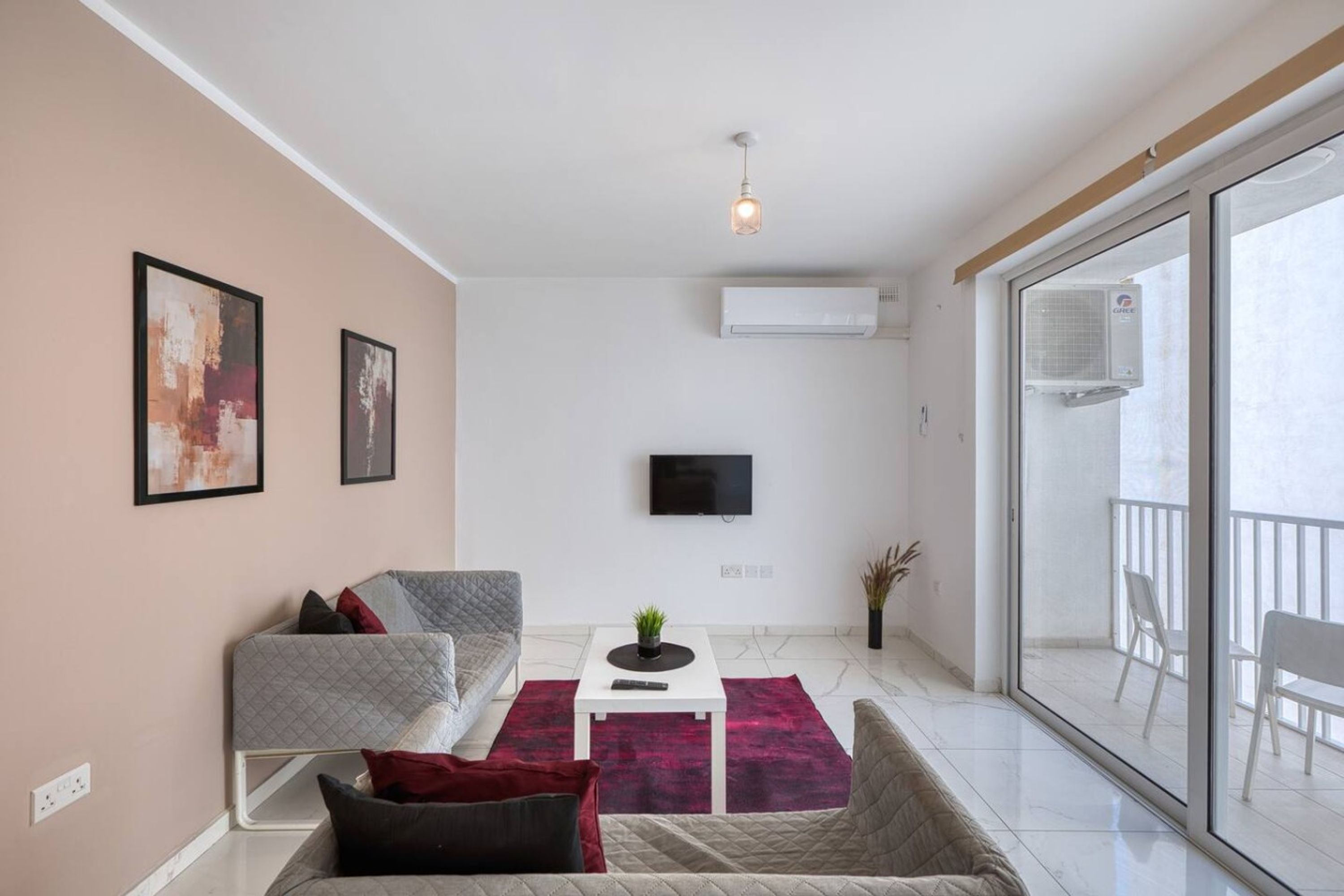 Una sala de estar moderna con un sofá, una mesa de centro, un televisor y un balcón con barandilla.