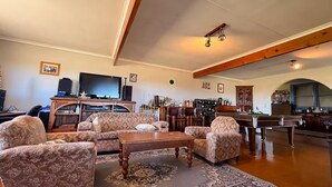 Un salon comprenant un canapé, des fauteuils, une table basse, un téléviseur et une table de billard.