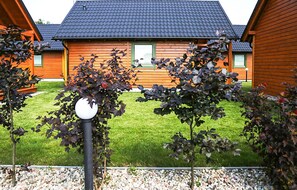 A wooden cabin with a tiled roof, surrounded by a well-maintained lawn and a gravel path. - Cozy home in Rozewie with sauna (Rozewie)