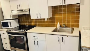 A kitchen with white cabinets, a microwave, an oven, a sink, and a tiled backsplash. - Spacious, Private & Independent Stay in Milton (Milton)