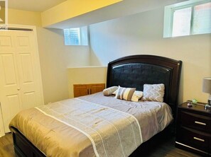 A bedroom with a bed, bedside table, and a window.