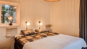 A bedroom with a bed, two bedside lamps, a window with a view of trees, and a wooden headboard. - Nice home in Alingsås (Alingsås)