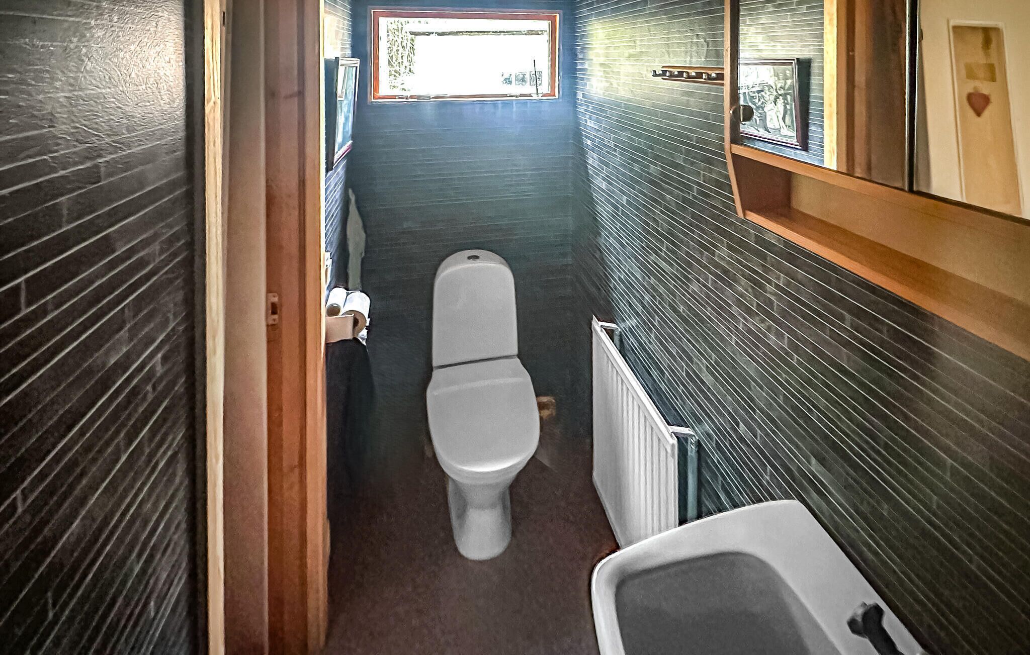 Une petite salle de bain comprenant des toilettes, un radiateur et un petit lavabo.