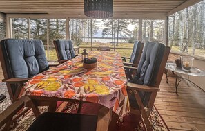 A covered outdoor dining area with a long table, chairs, and a view of a forested landscape. - 2 bedroom stunning home in Kristinehamn (Kristinehamn)