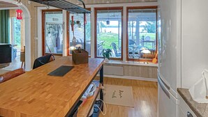 Een eethoek met een houten tafel, stoelen, een radiator en uitzicht op de omgeving.