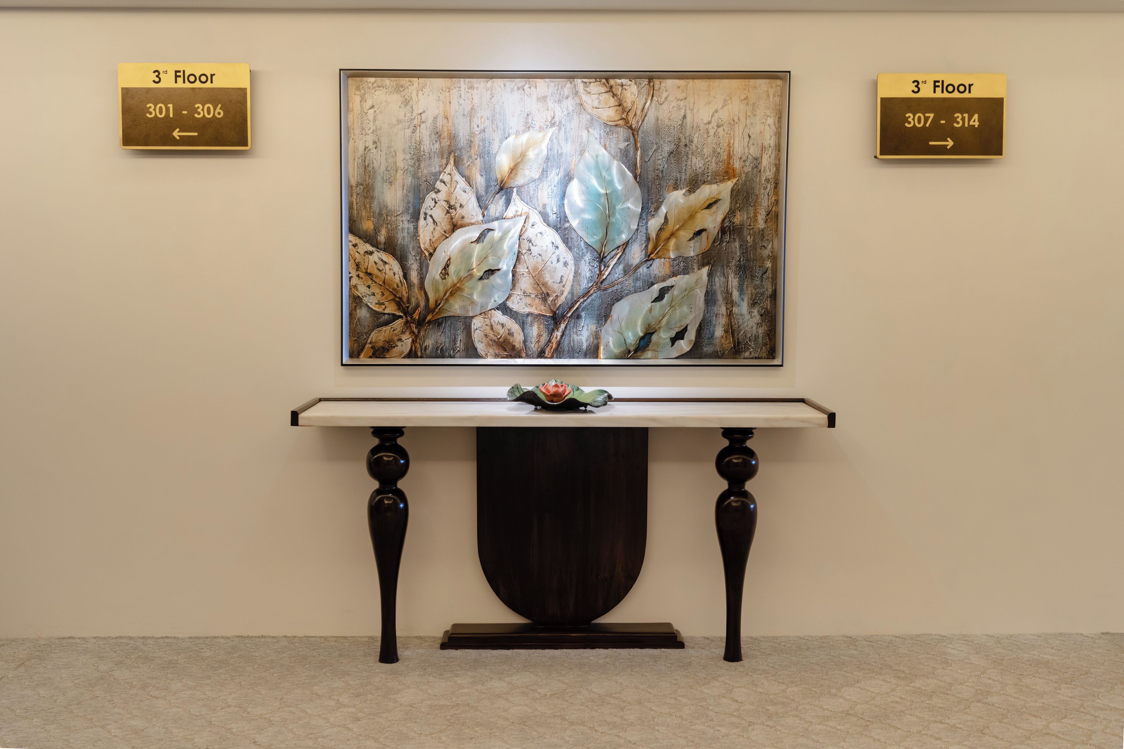A framed artwork on a wall with directional signs indicating room numbers and floor level.