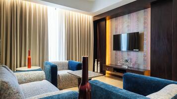 Una sala de estar moderna con un conjunto de sofá, una mesa de centro, un televisor de pantalla plana montado en una pared con diseño, y un ventanal con cortinas.
