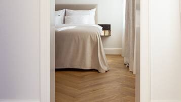 Una camera da letto con un letto, un comodino e un pavimento in legno.