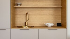 A modern kitchen with a built-in sink, wooden shelves, and a minimalist design. - Sugar Factory Apartments (Kotka)