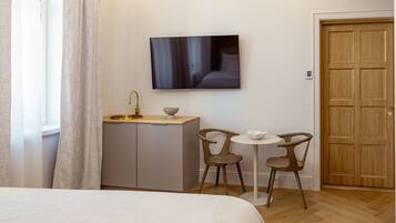 Une chambre d’hôtel avec un lit, un téléviseur fixé au mur, une petite kitchenette et deux chaises autour d’une table.
