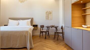 A hotel room with a bed, a small table with chairs, a decorative wall piece, and a wooden cabinet.